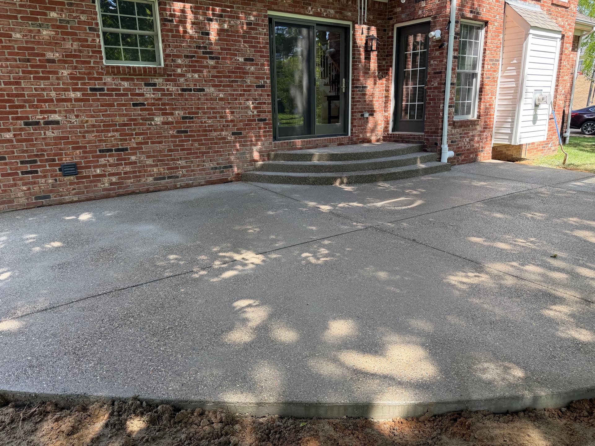 Sunken Paver Patio Replaced With a Larger Exposed Concrete Outdoor Patio image